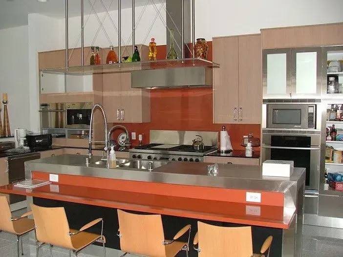 A kitchen with stainless steel appliances and orange cabinets