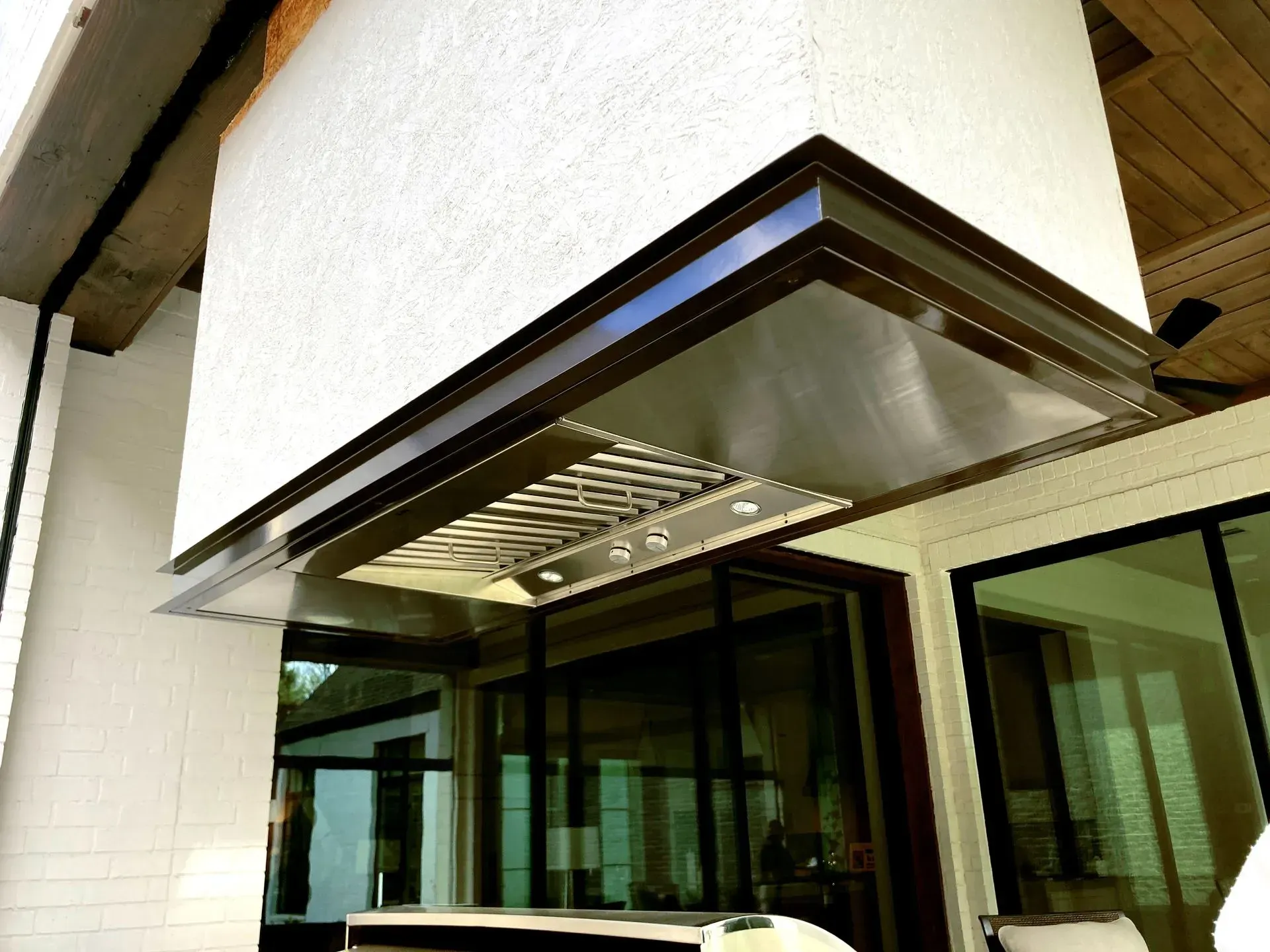 A stainless steel hood is hanging from the side of a building