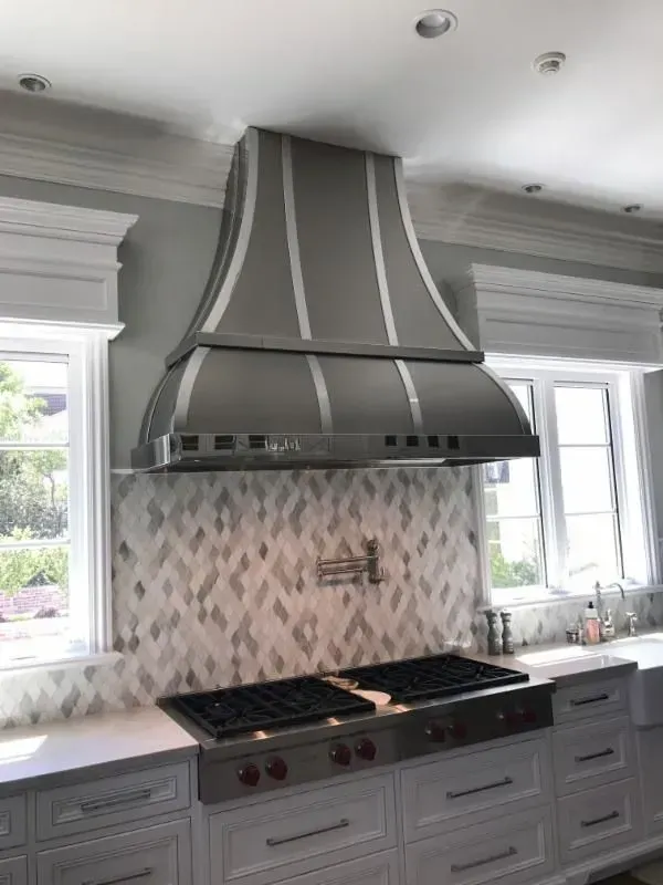 A kitchen with a stove top oven and a stainless steel hood.
