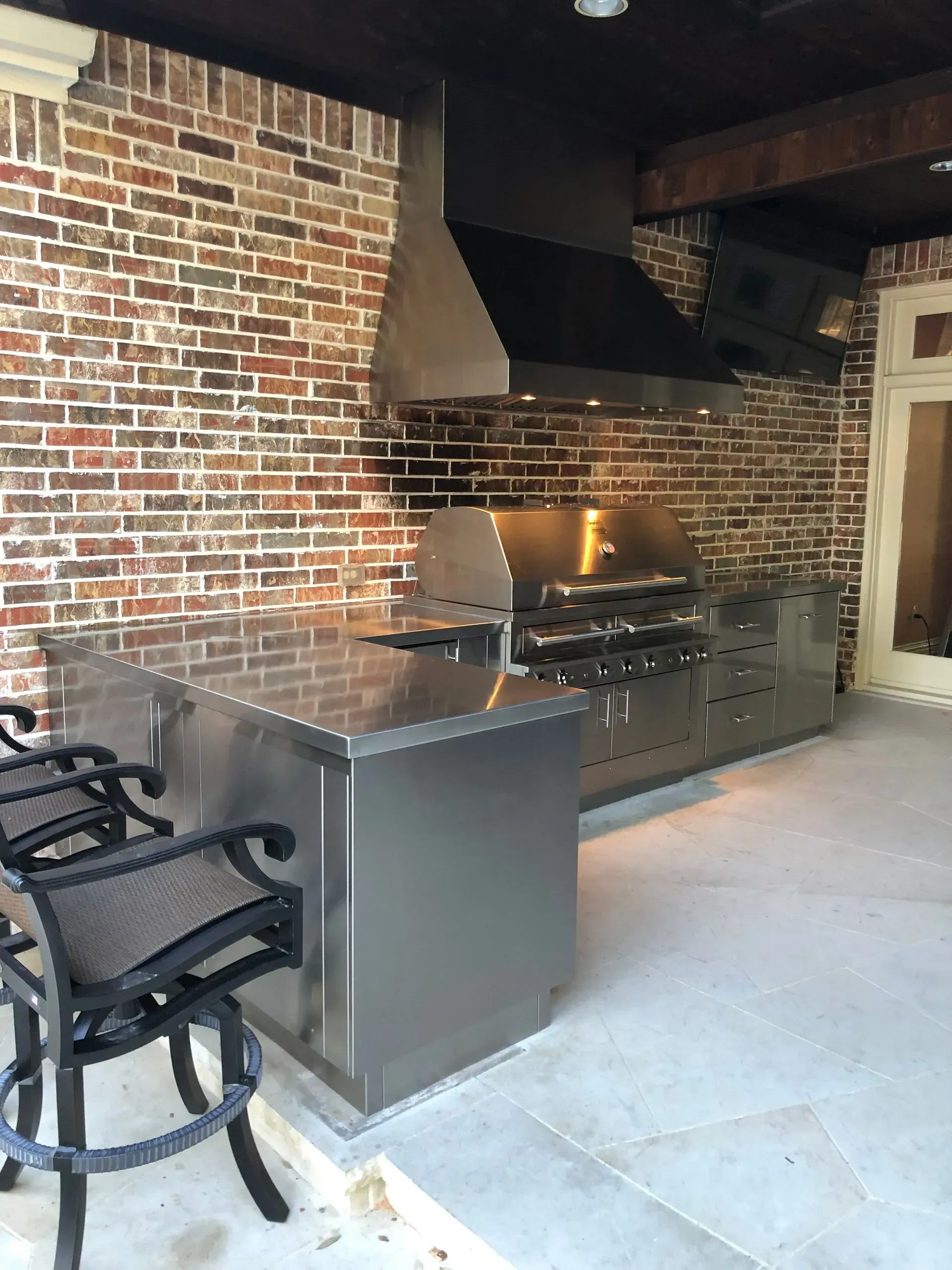 A kitchen with a brick wall and a stainless steel counter top.