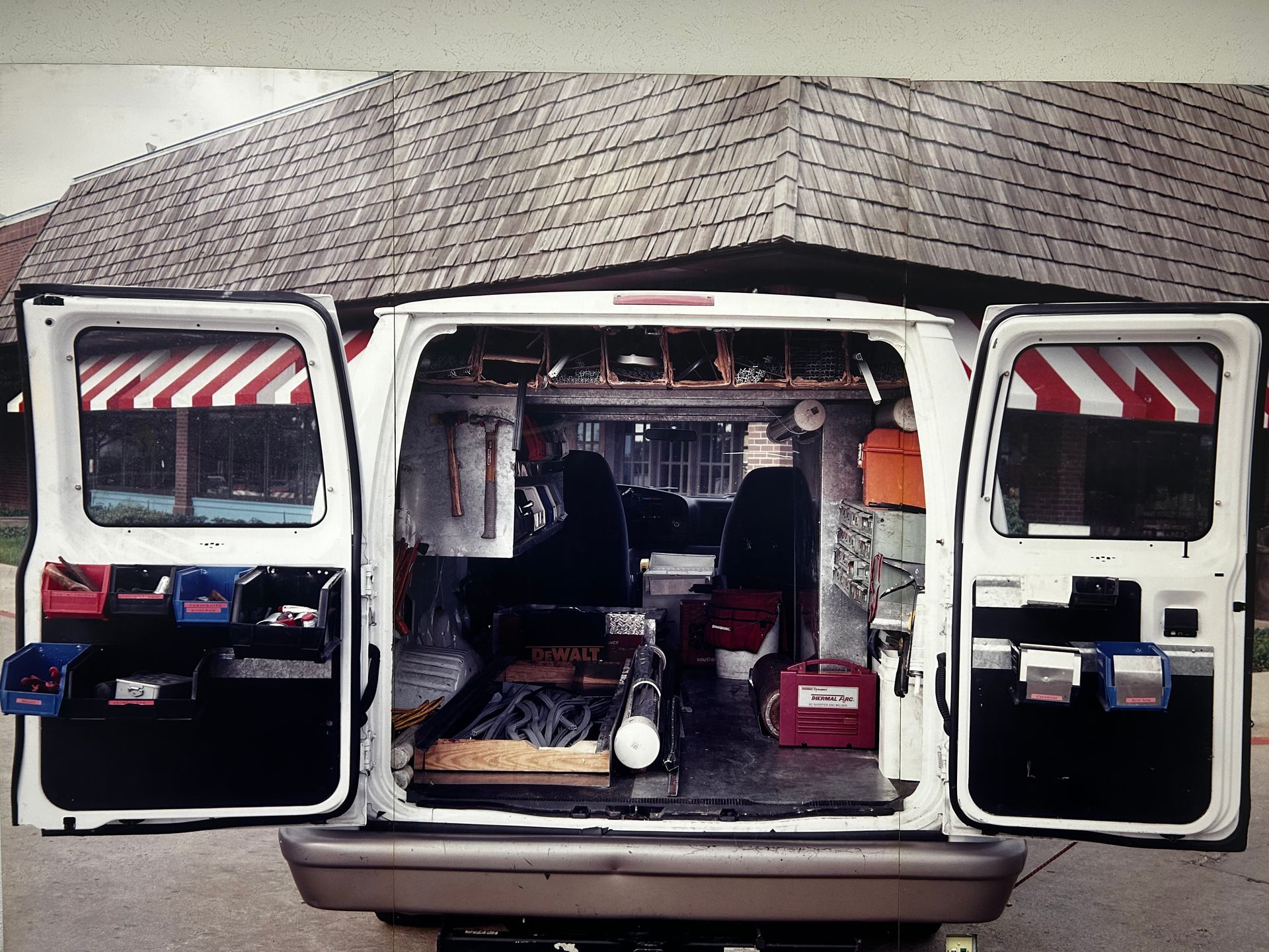 A white van is parked in front of a building with its doors open