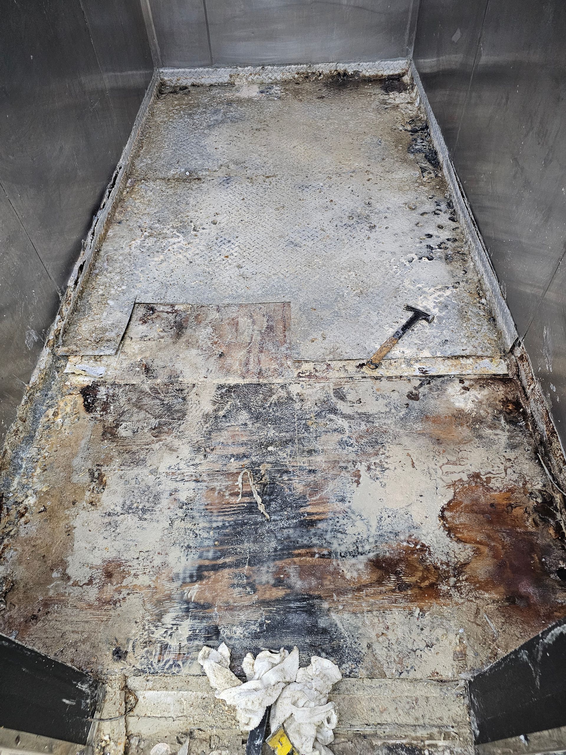 A dirty concrete floor with a hammer on it.