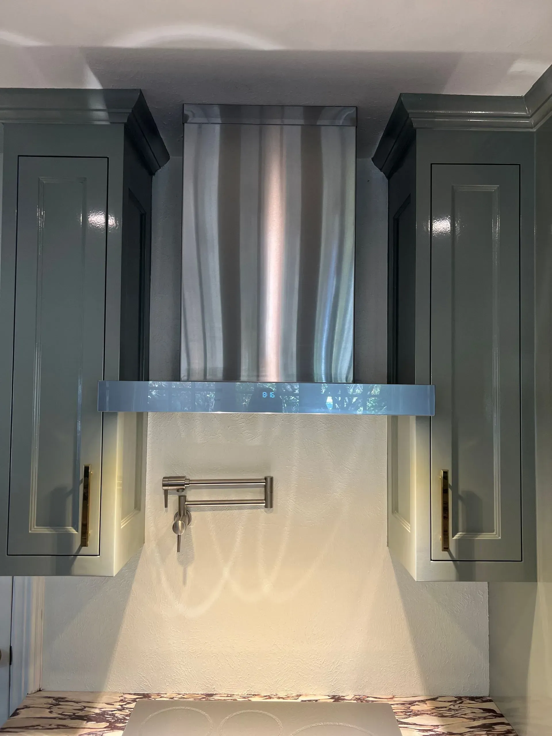 A kitchen with blue cabinets and a stainless steel hood