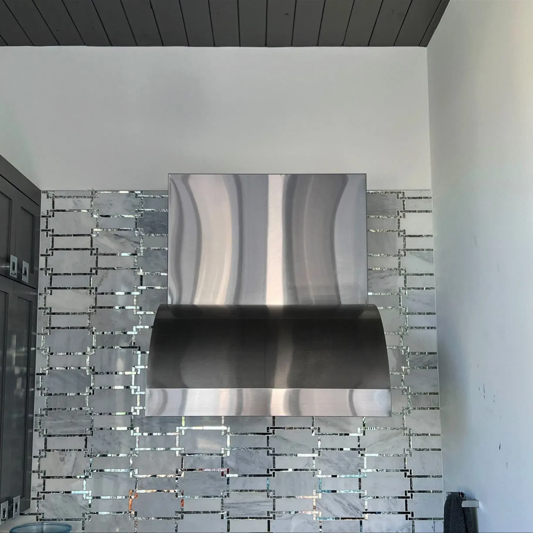 A stainless steel hood is hanging from the ceiling in a kitchen