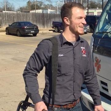 A man in a gray shirt is standing in front of a truck.