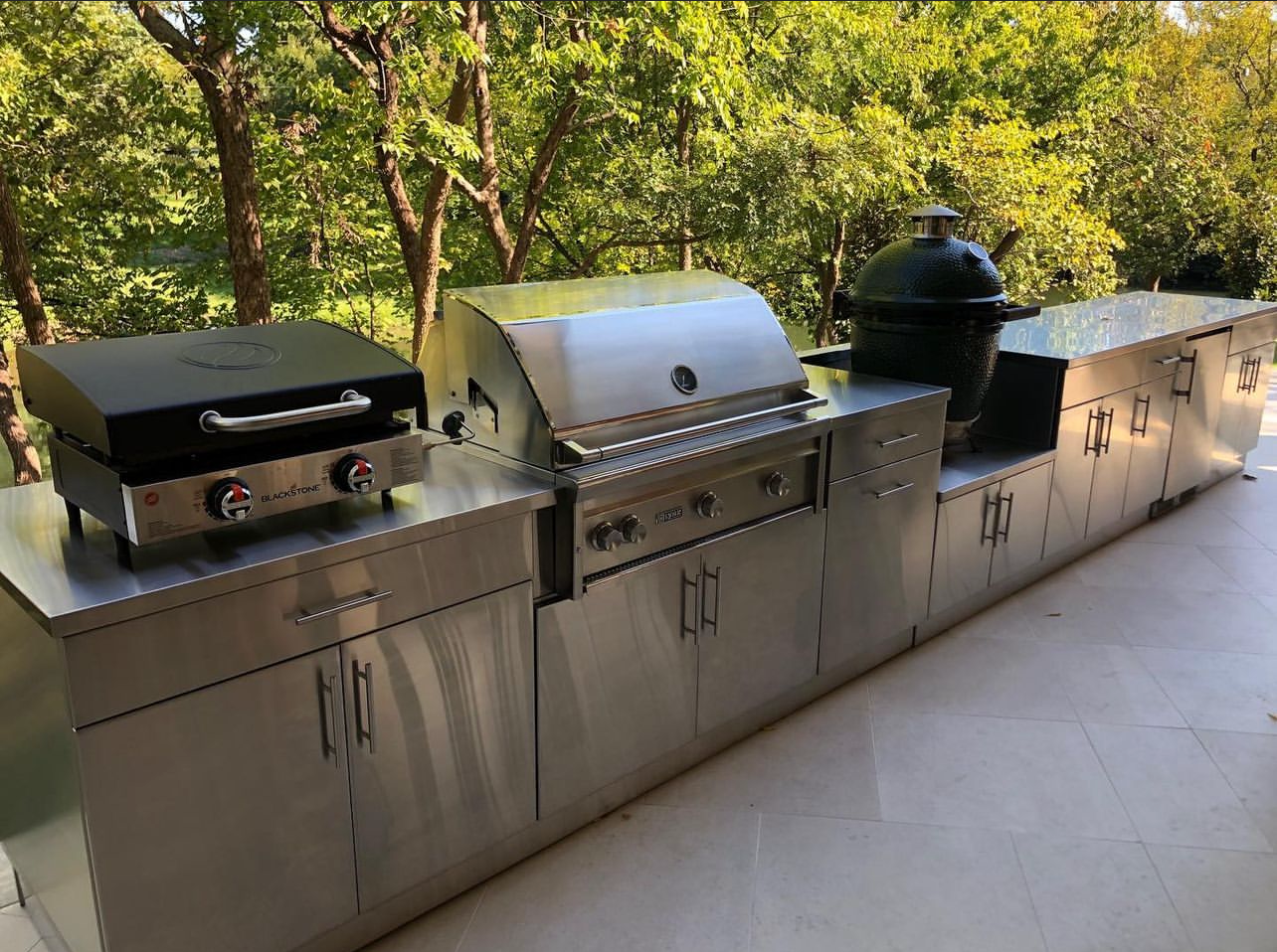 A large outdoor kitchen with stainless steel cabinets and a grill.