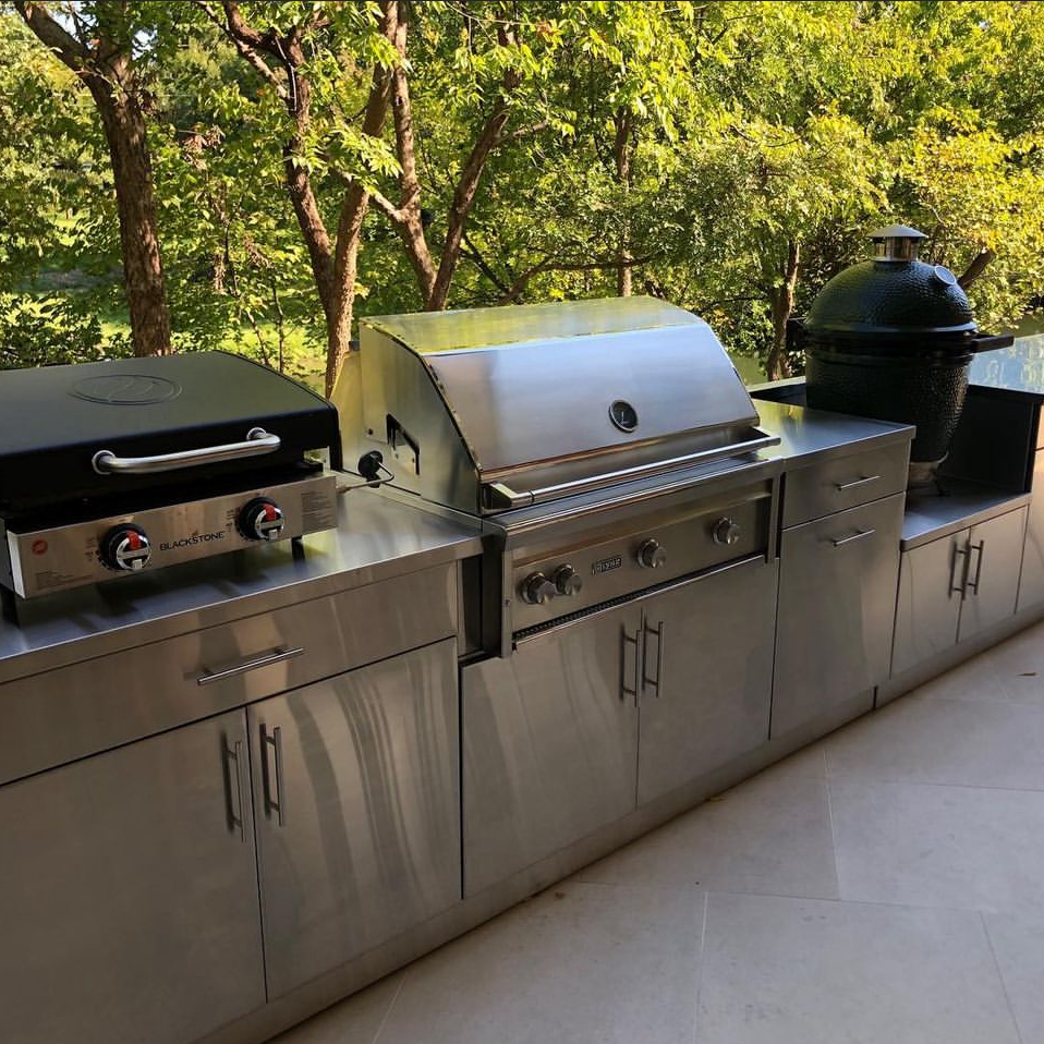 An outdoor kitchen with stainless steel cabinets and a grill
