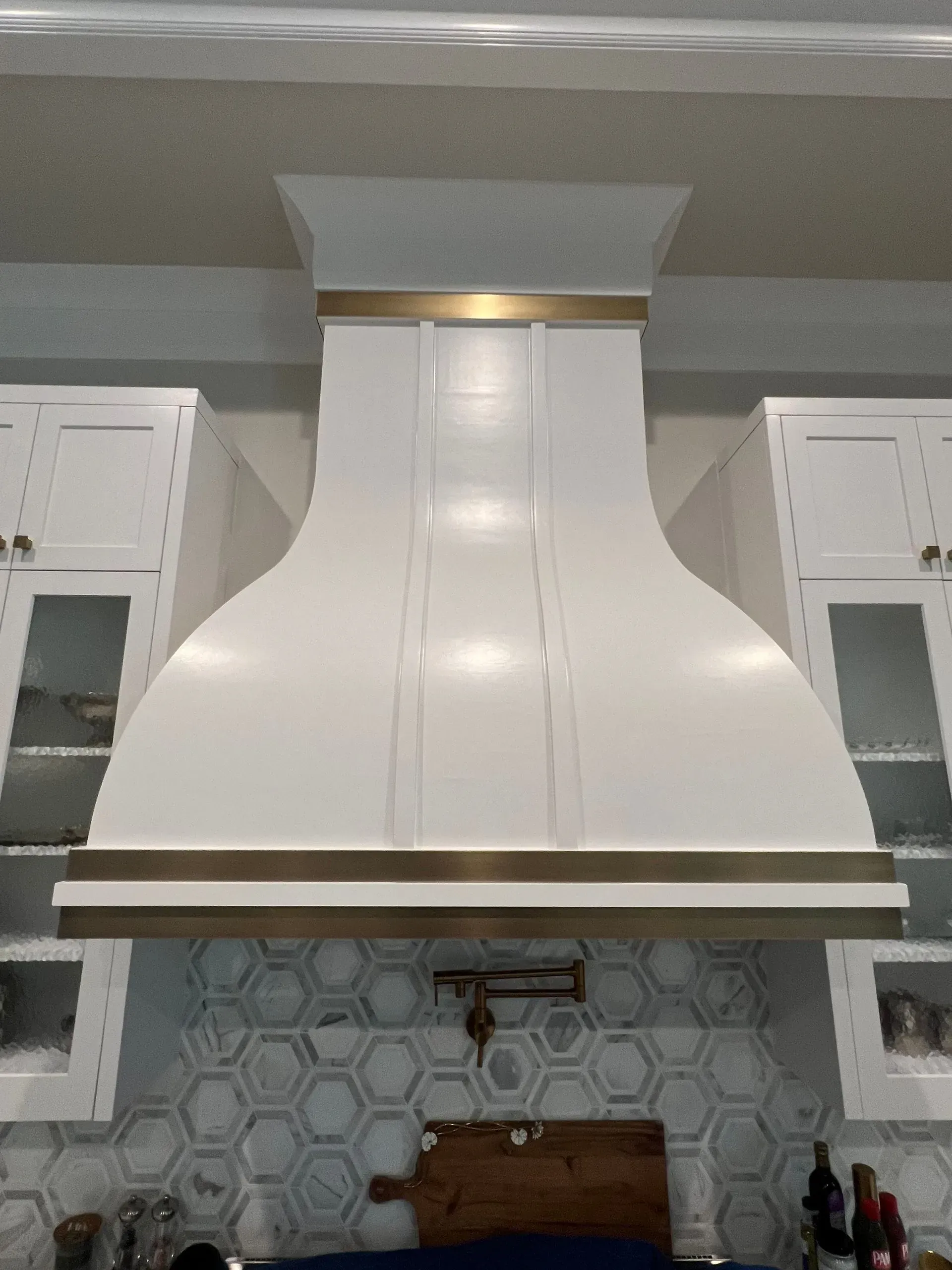 A white hood is hanging from the ceiling in a kitchen.