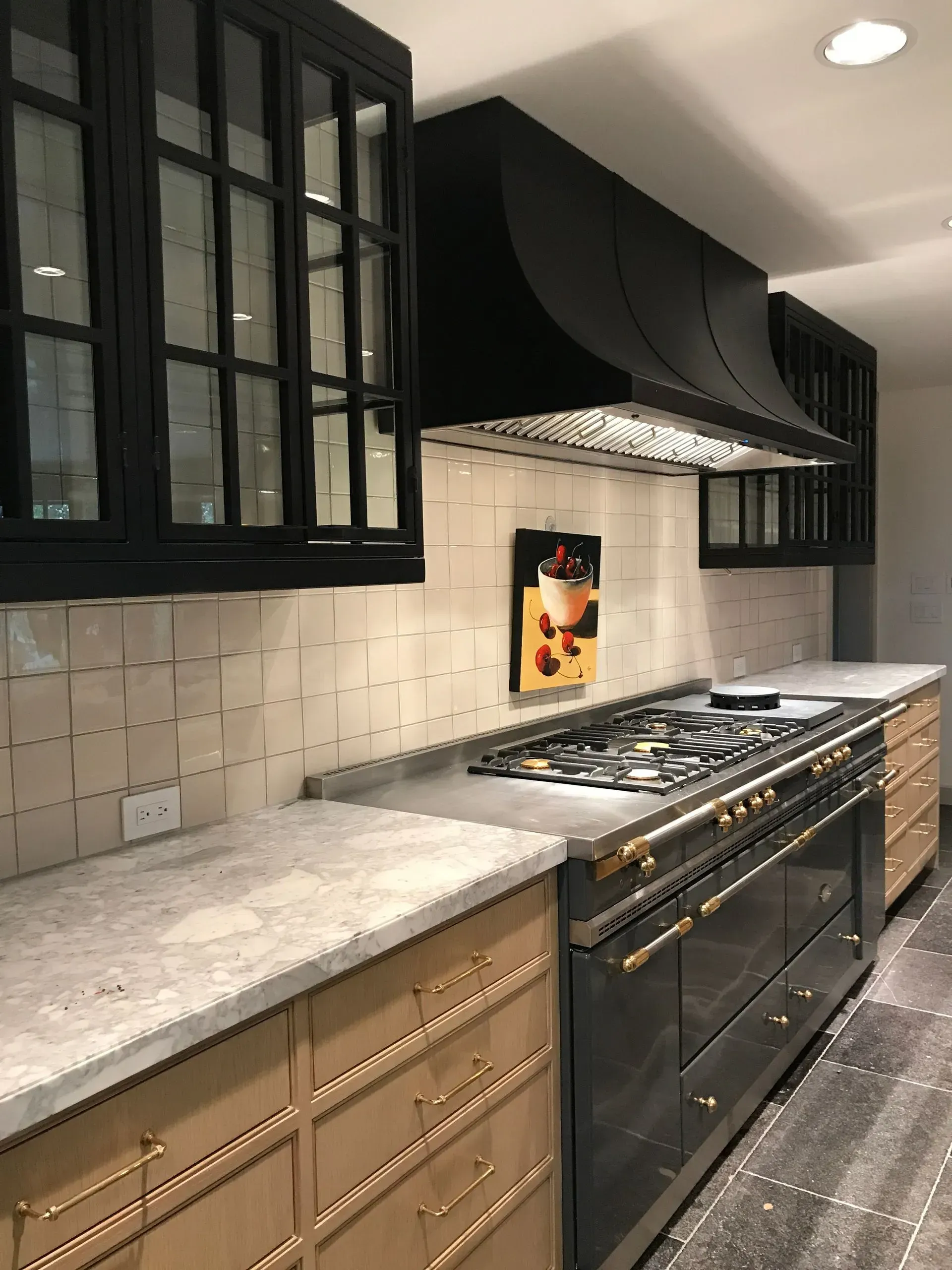 A kitchen with a stove , oven , cabinets and a painting on the wall.