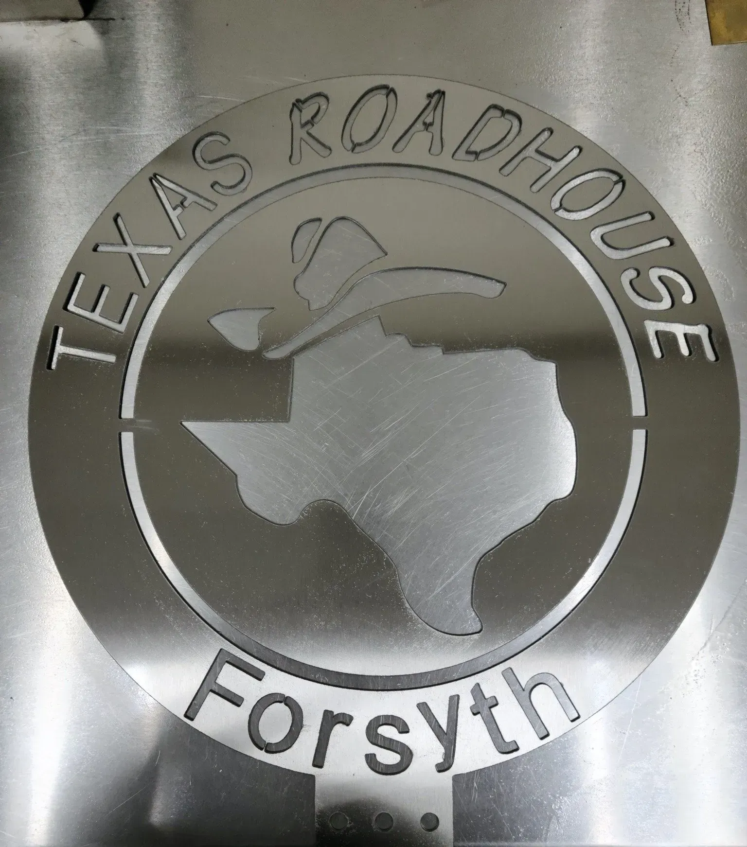 A metal sign that says texas roadhouse forsyth