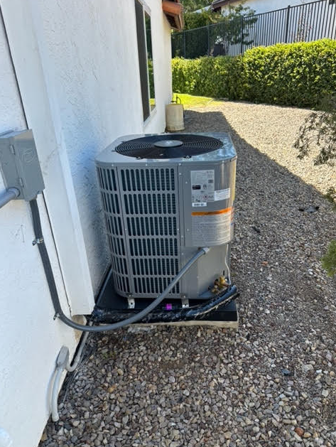 A man is working on an air conditioner with a drill.