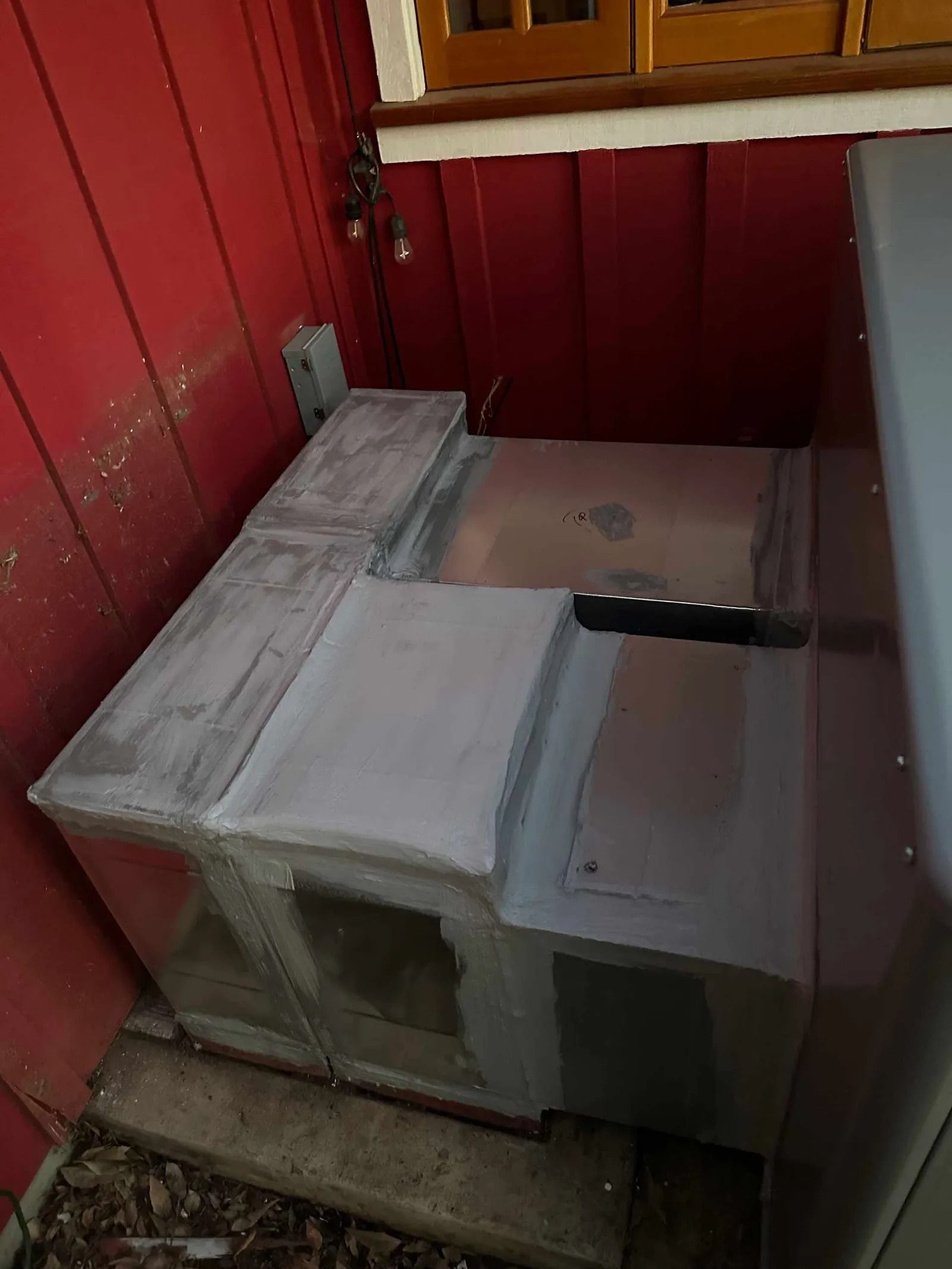 A refrigerator is sitting on the ground in front of a red wall.