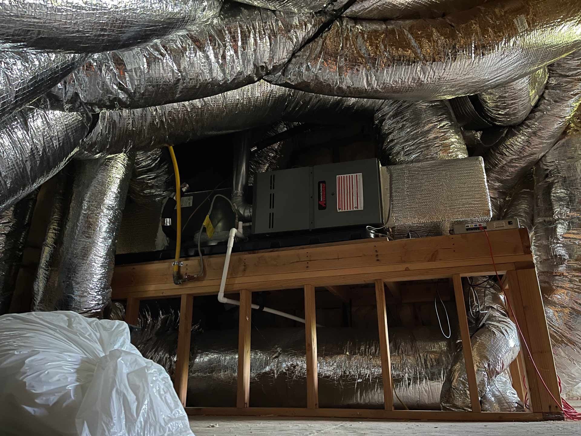 An air conditioner is sitting in the attic of a house.