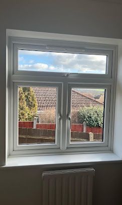 A white window with a view of a house and a radiator in a room.