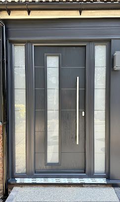 A black front door with a stainless steel handle on a house.