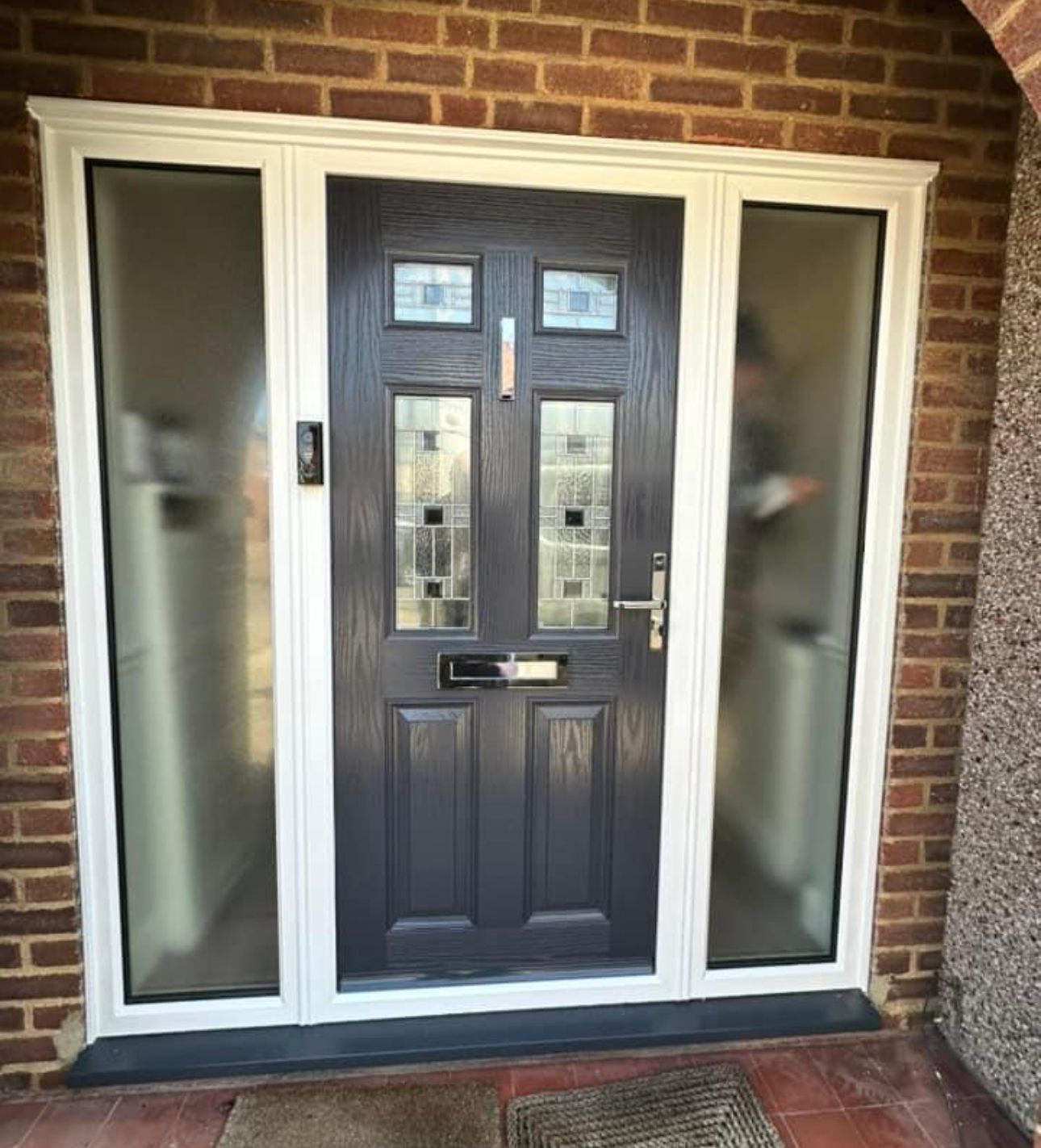 A black front door with a white frame is sitting on a brick wall.