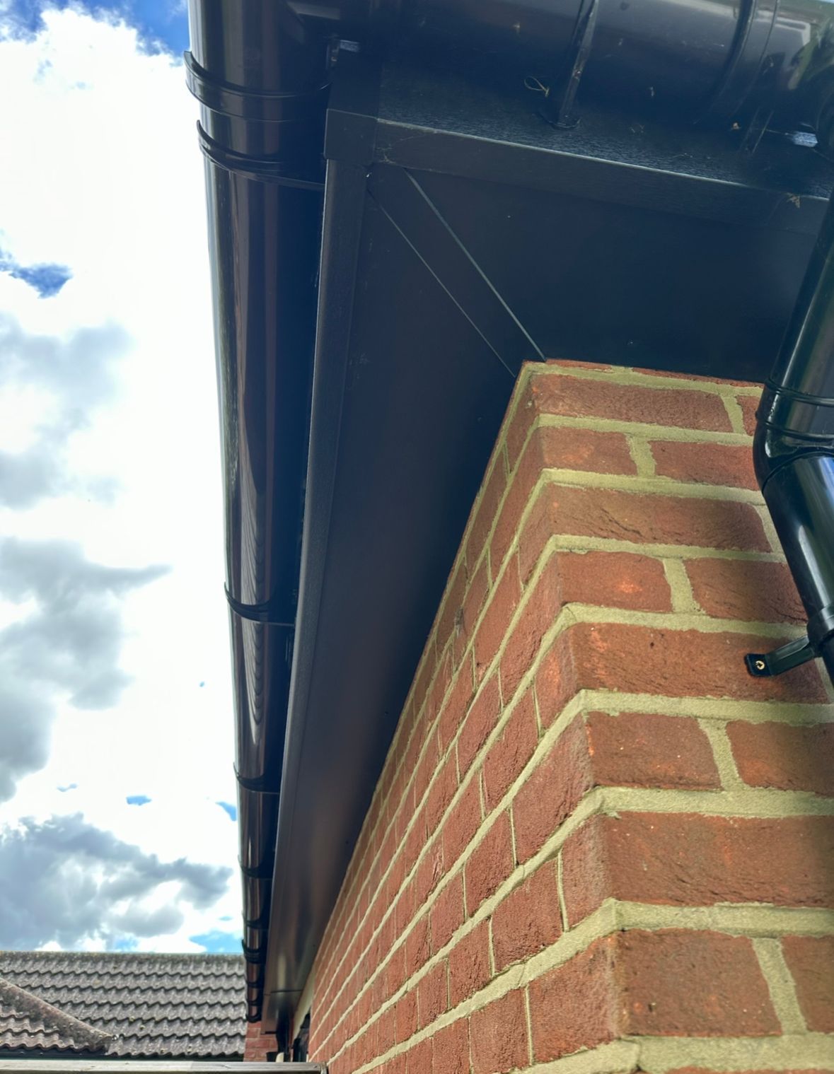 A brick building with a black gutter on the side of it.