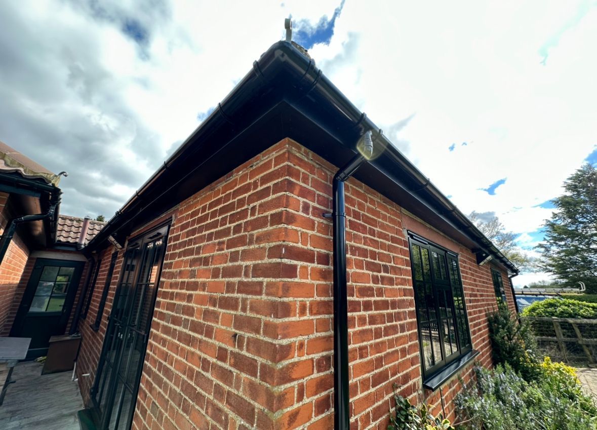 A brick building with a black gutter on the side of it.