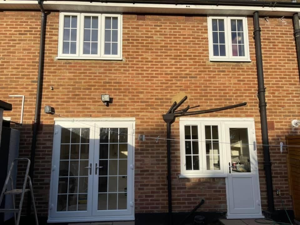 The back of a brick house with white windows and french doors.