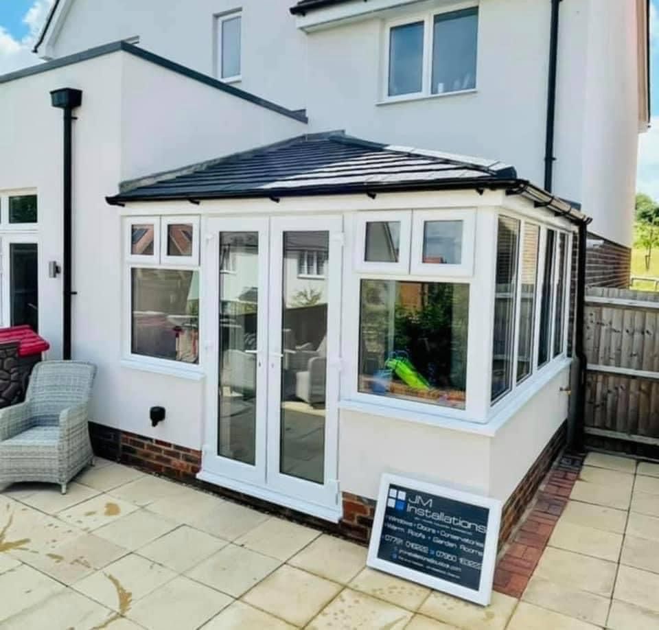 A white house with a conservatory on the side of it.