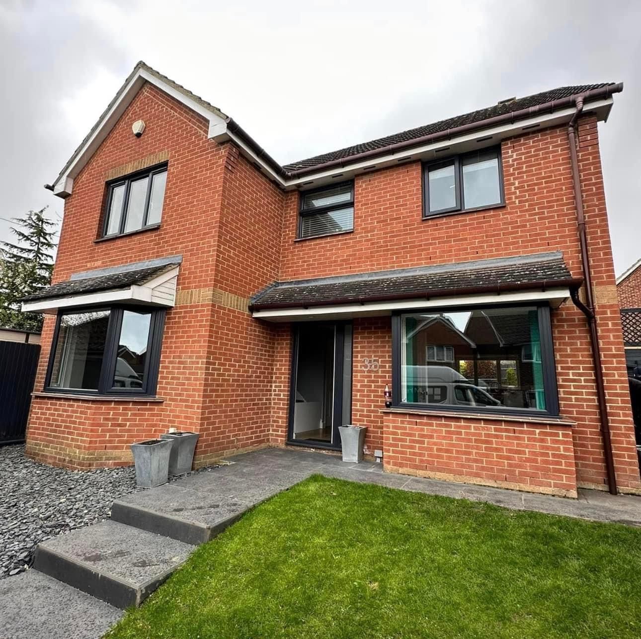 A large red brick house with a lush green lawn in front of it.