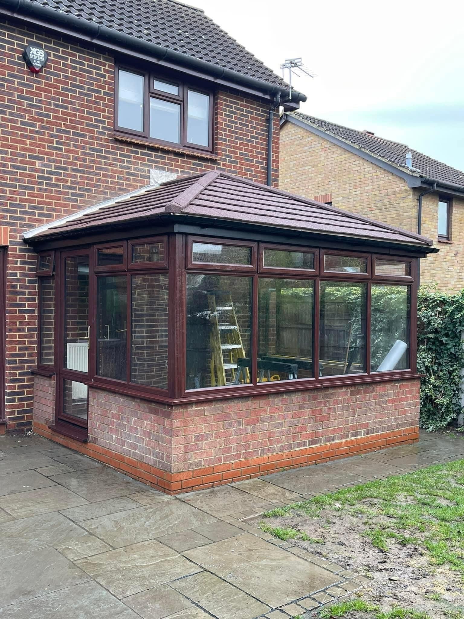 A conservatory is being built on the side of a brick house.