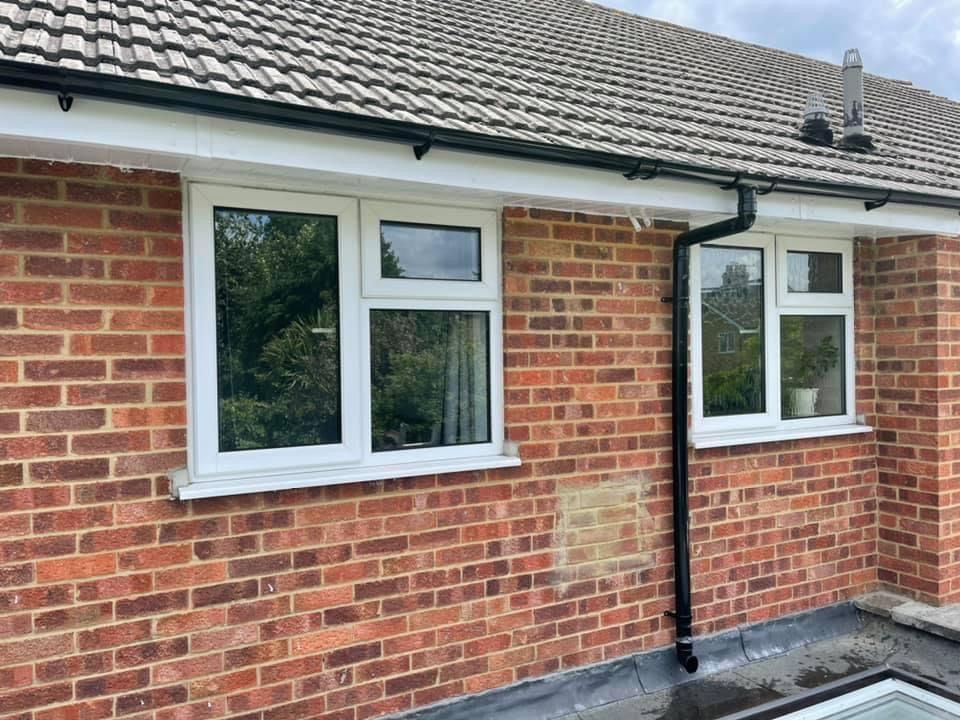 A brick house with white windows and a black gutter.