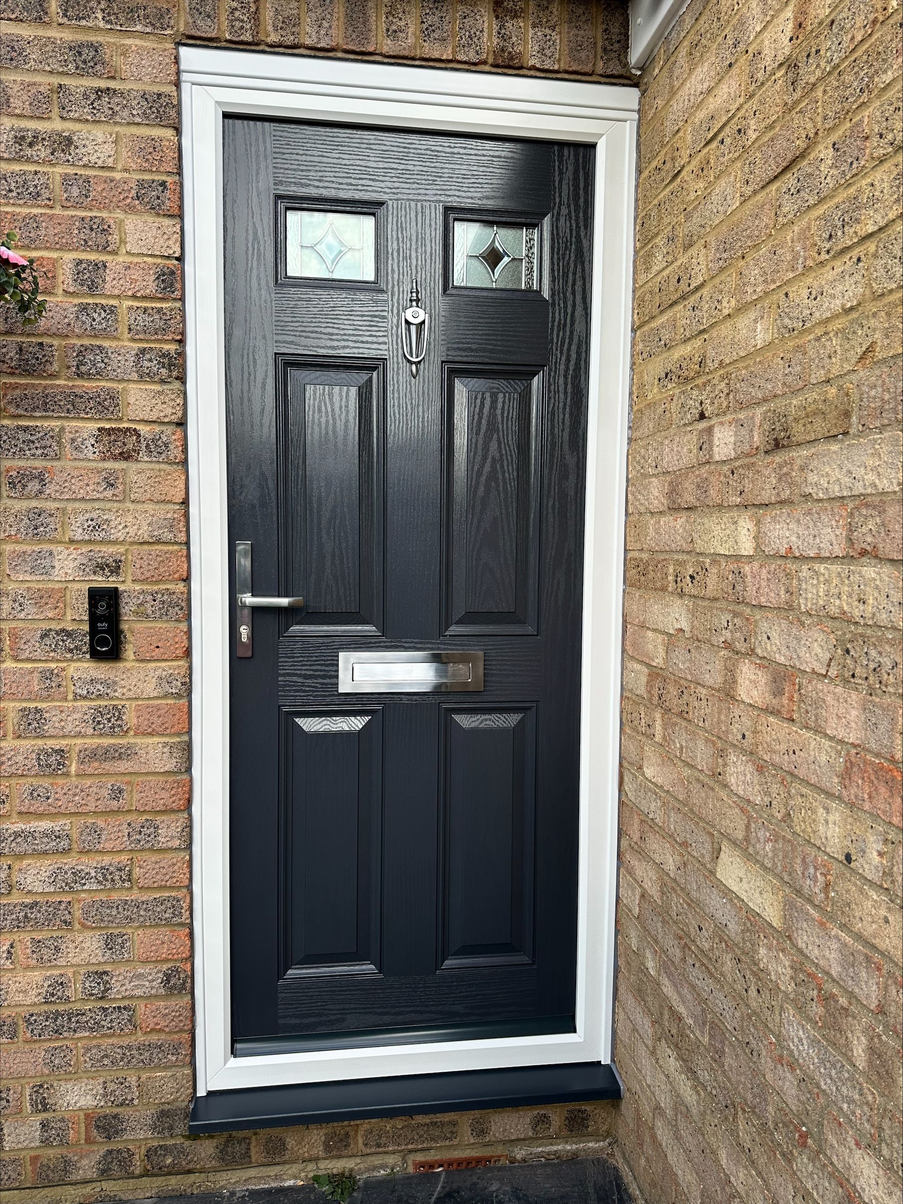 A black door with a white trim is on a brick wall.
