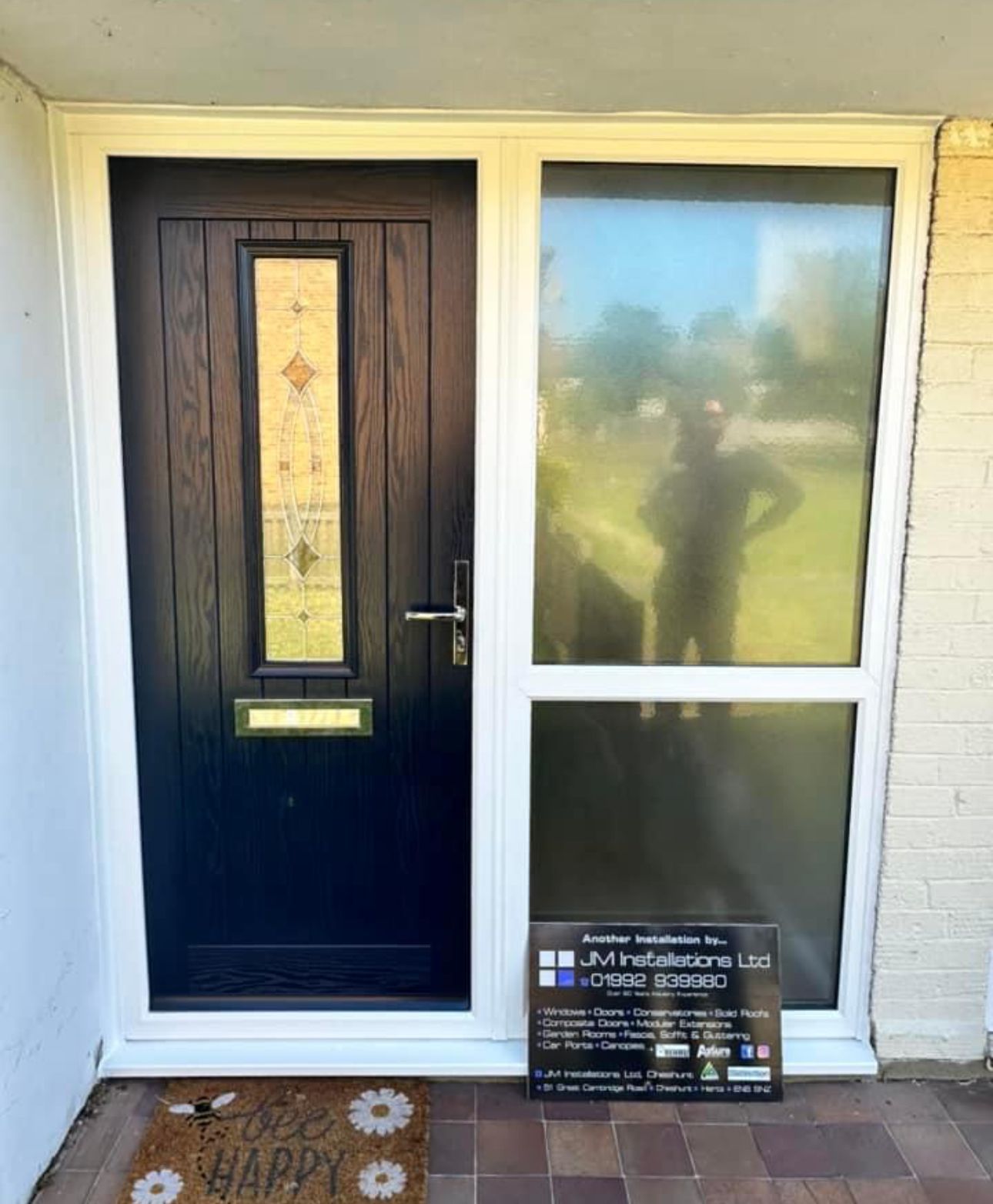 A black door with a white frame and a door mat that says happy