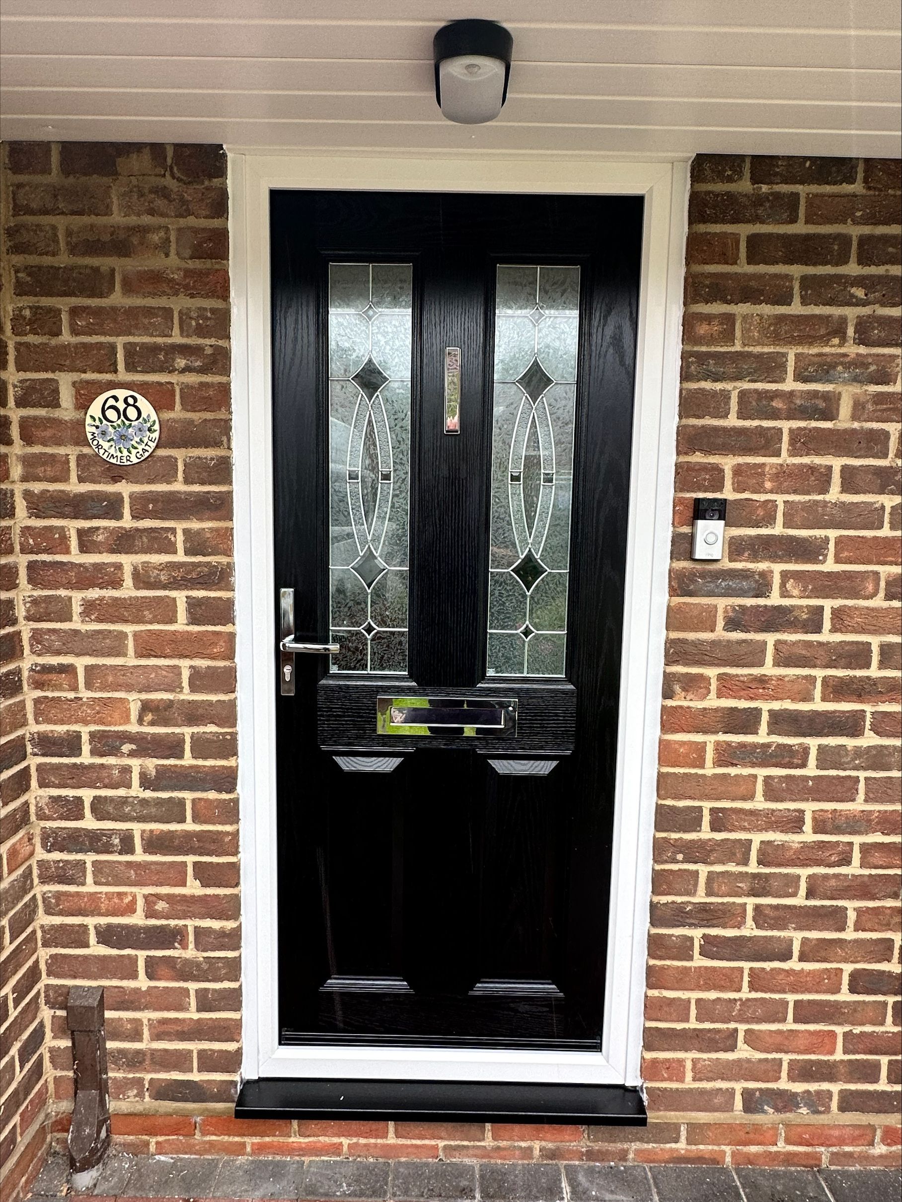A black door with a white trim is on a brick wall.