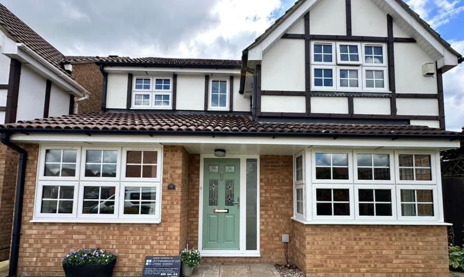 A brick house with white windows and a black door