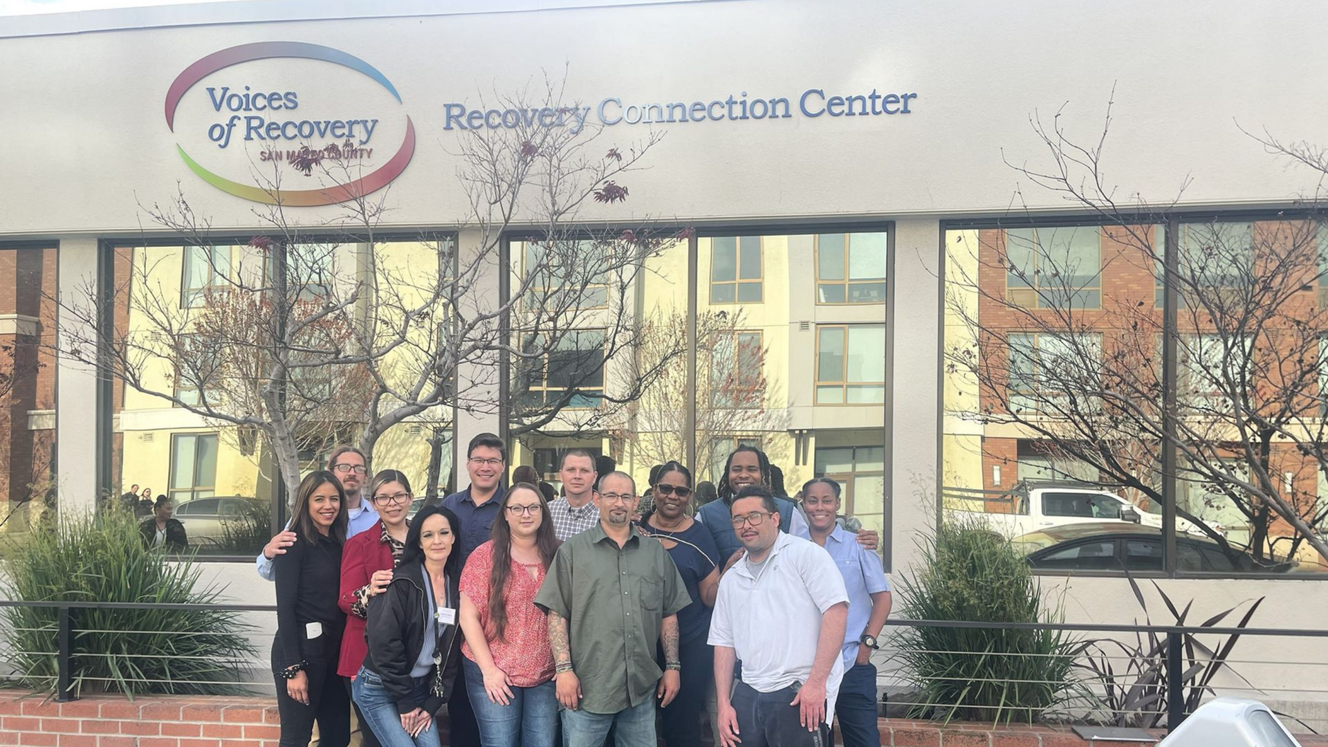 Group of people smiling in front of a building with 