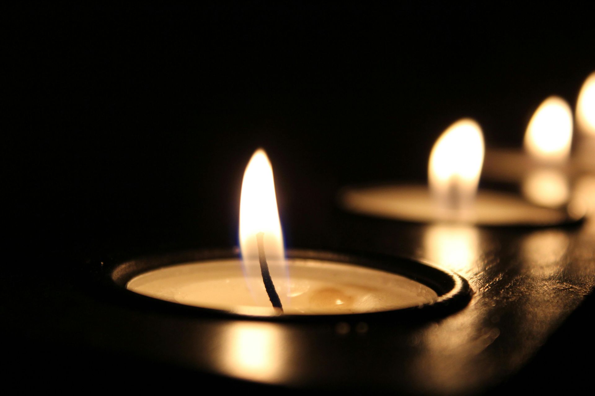 Candle flames in dark setting; soft, warm glow.