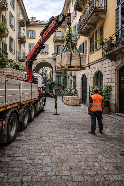 Scarico Travertino Romano in cortile interno a Torino con gru e camion su strada stretta