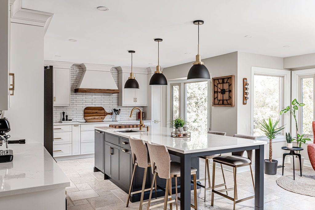 Spacious modern kitchen with a large island, pendant lights, white cabinets, and bar stools.