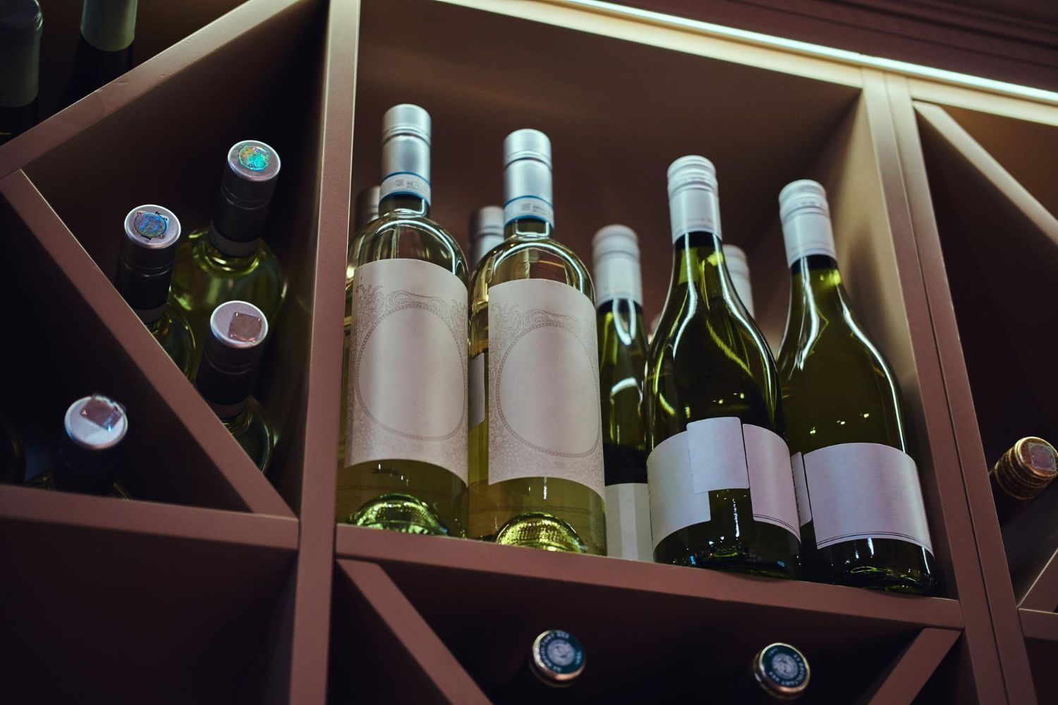 A row of wine bottles sitting on top of a wooden shelf.