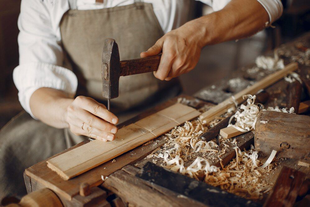 A man is hammering a nail into a piece of wood.
