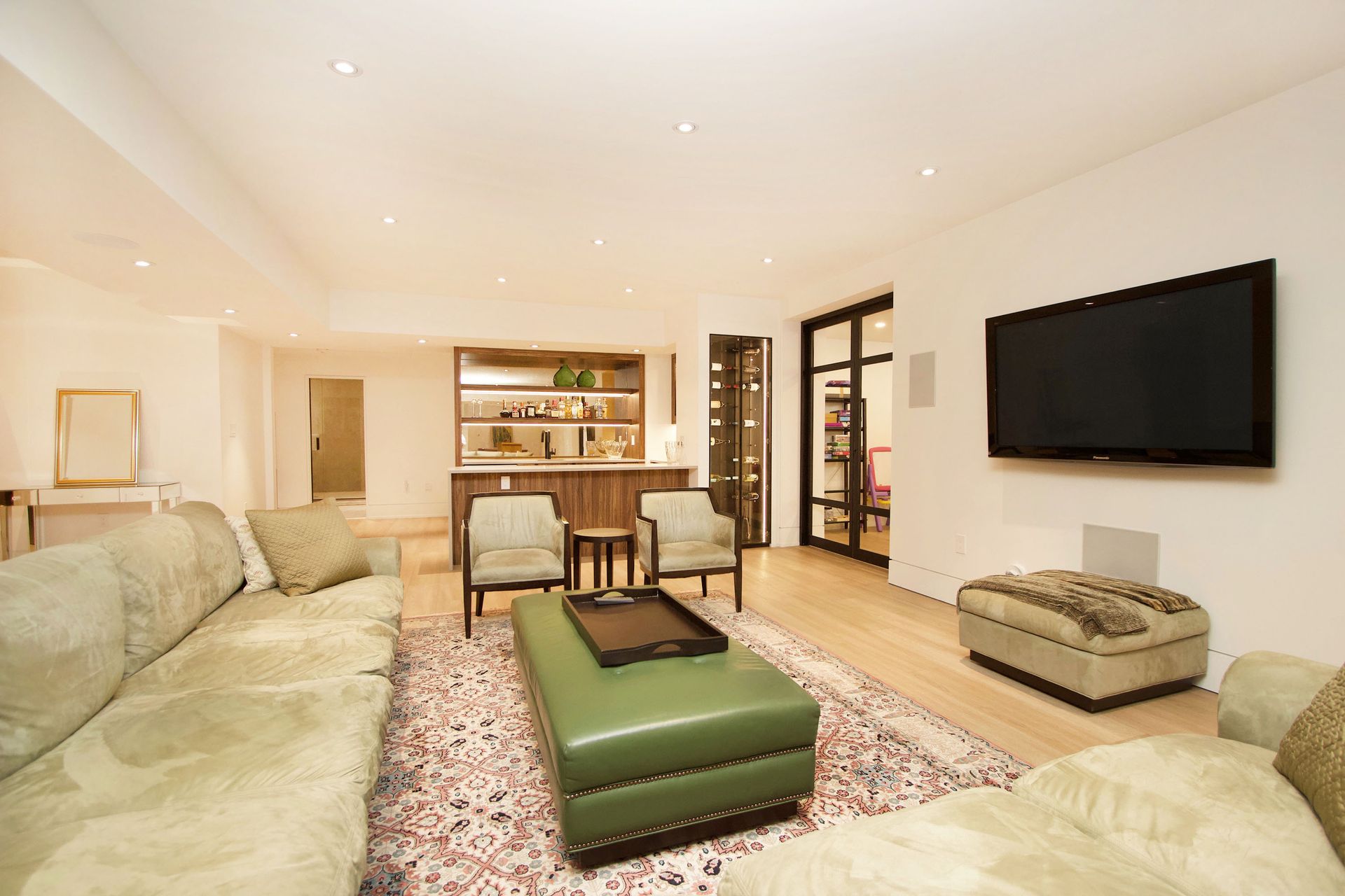 Living room with light wood floors, a large sofa, chairs, and a mounted television.