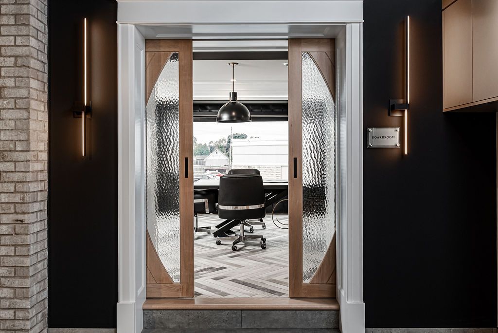 Open office doorway with textured glass panels and a view into a modern workspace with desk and chair.