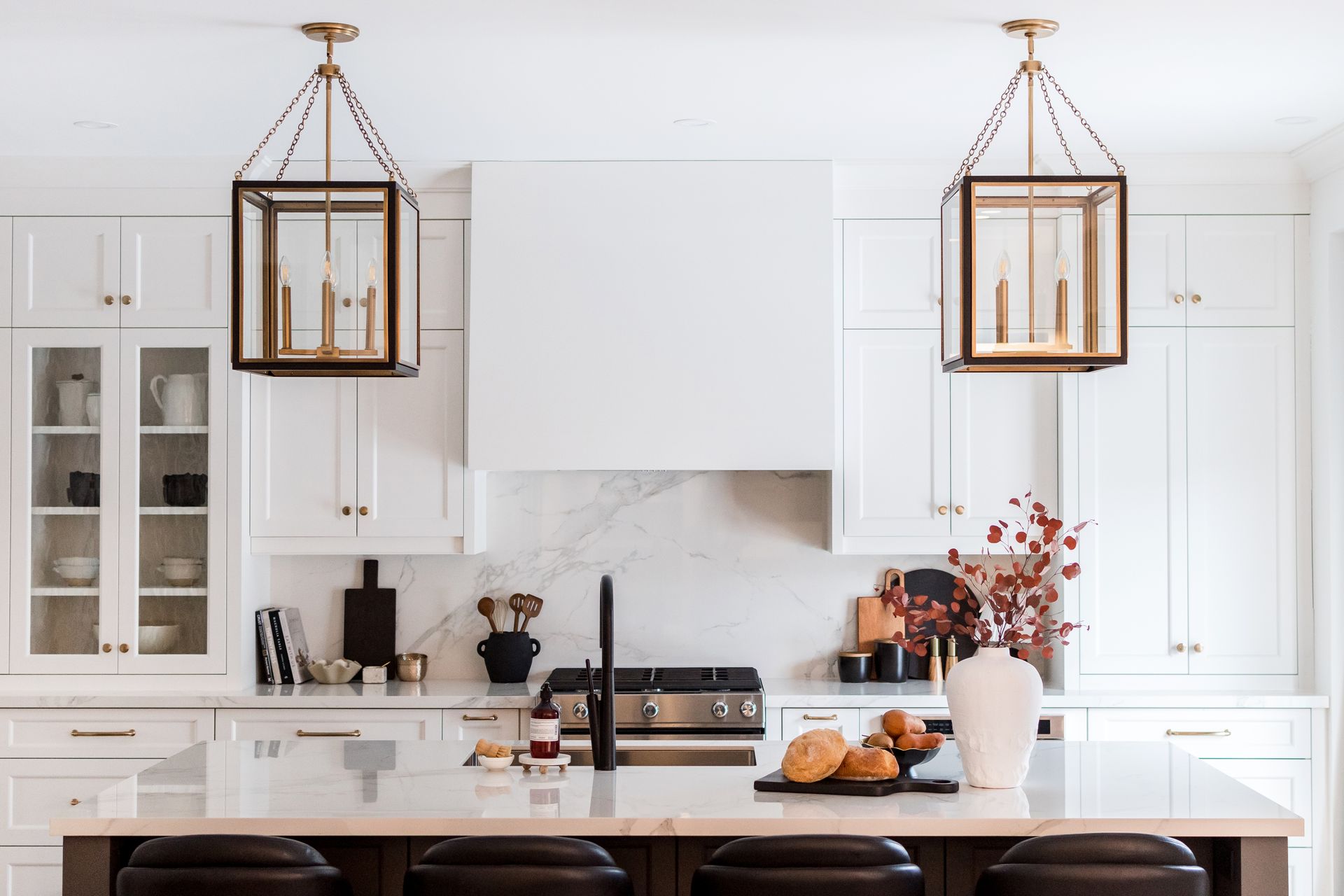 A kitchen with white cabinets , a stove , a sink , and a large island.