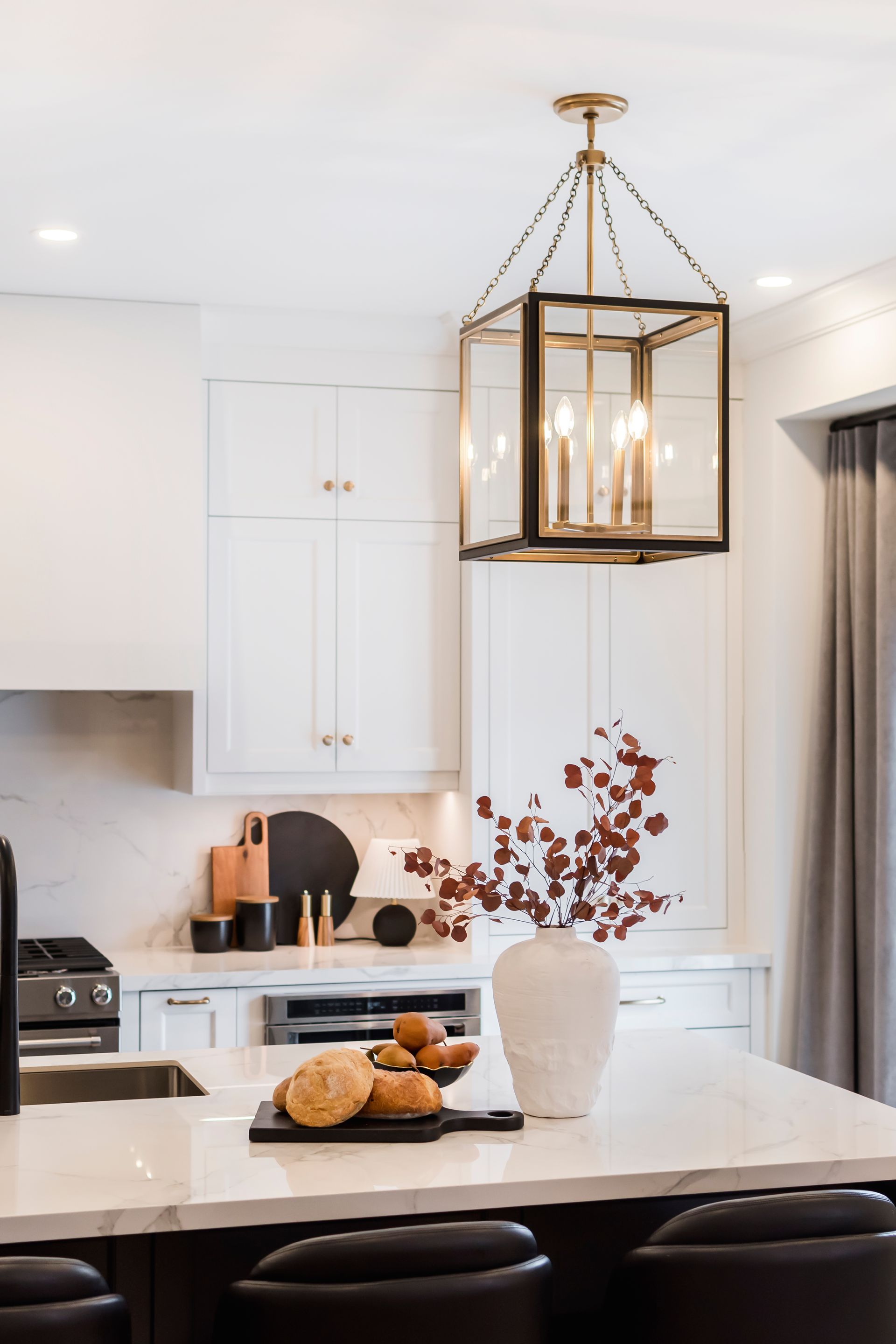 A kitchen with white cabinets , a sink , and a lantern hanging from the ceiling.