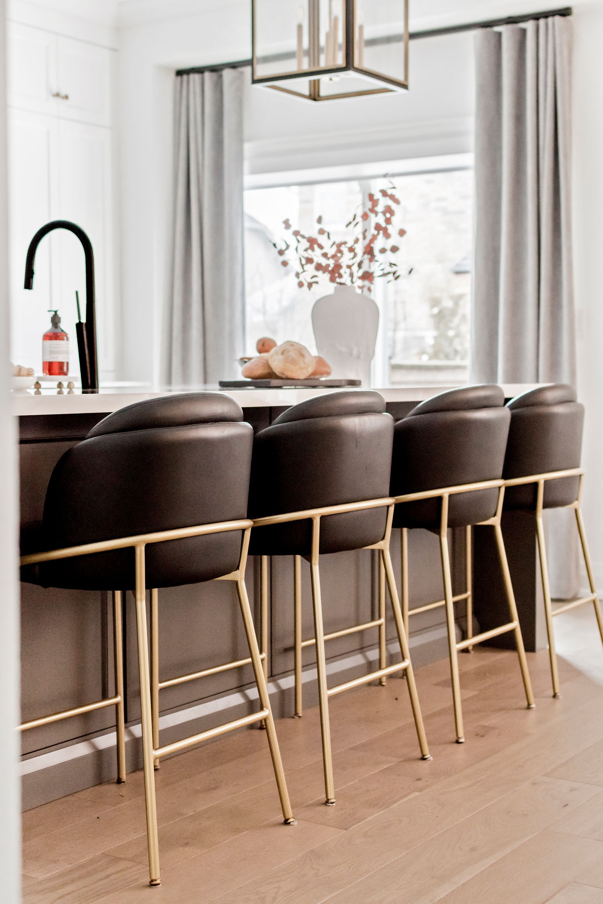 A kitchen with a row of bar stools and a sink.