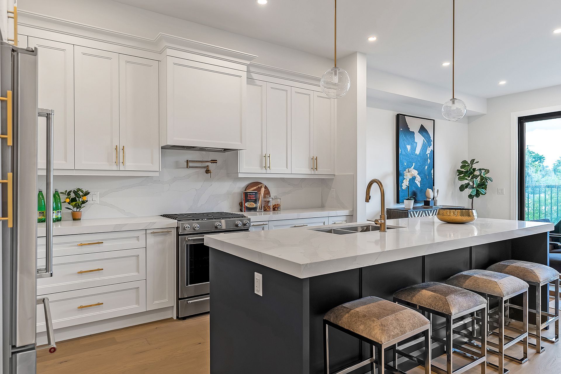 A kitchen with white cabinets , stainless steel appliances , a large island and stools.