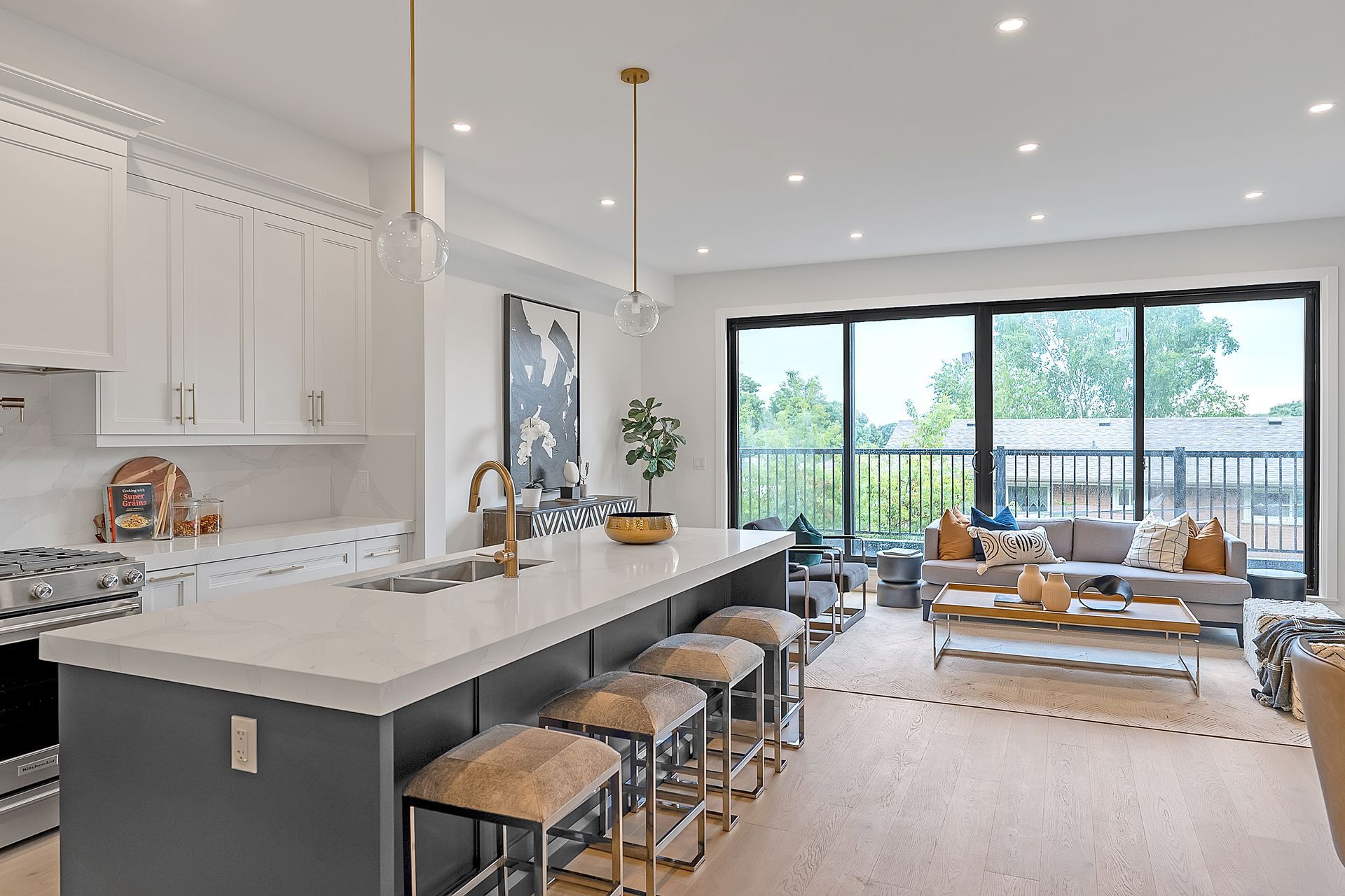 A kitchen with a large island and stools in a living room.