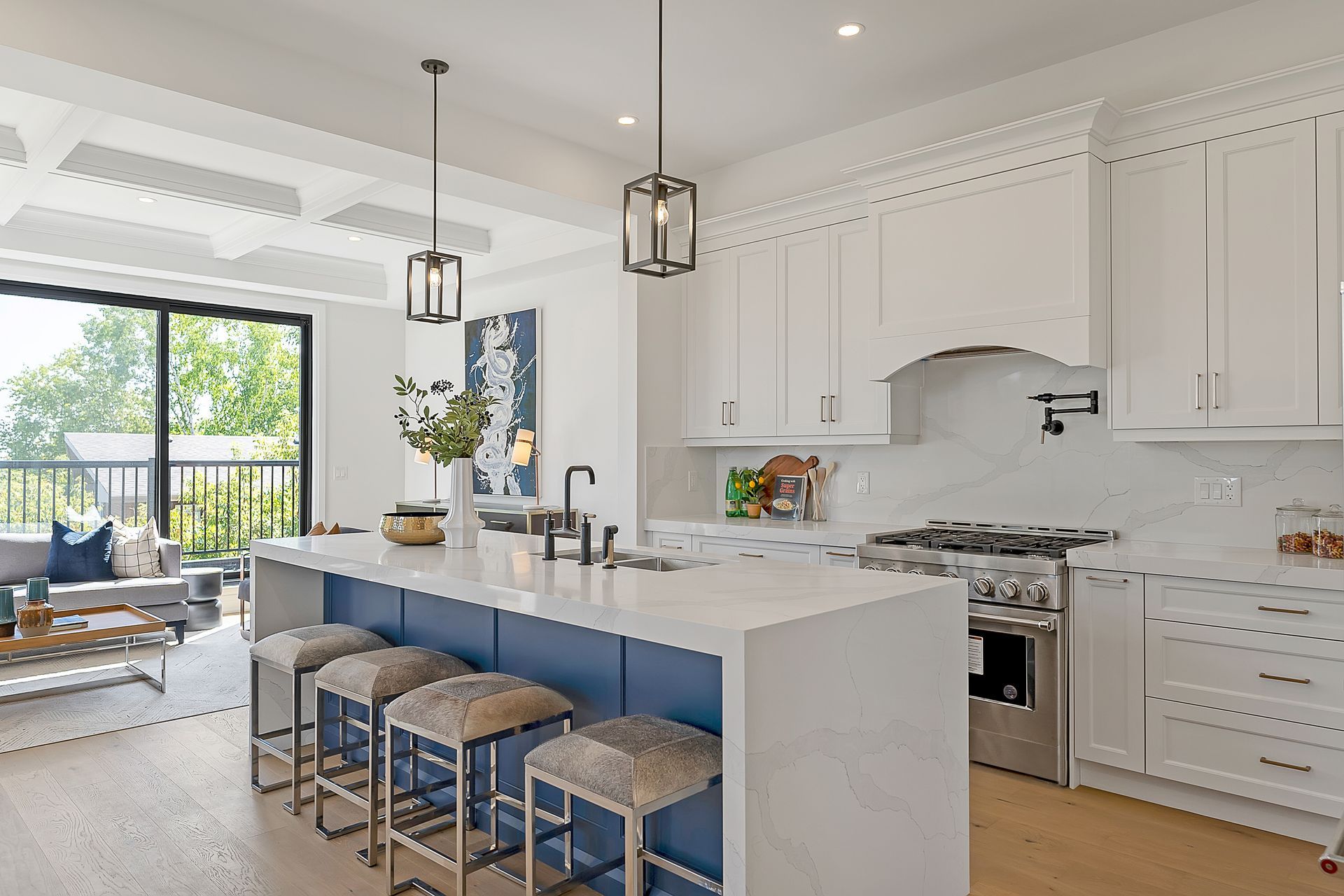 A kitchen with white cabinets and a blue island with stools.