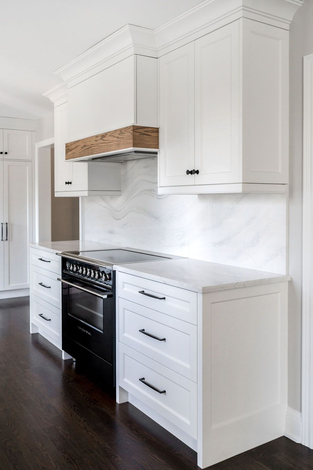 A kitchen with white cabinets and a black stove top oven.