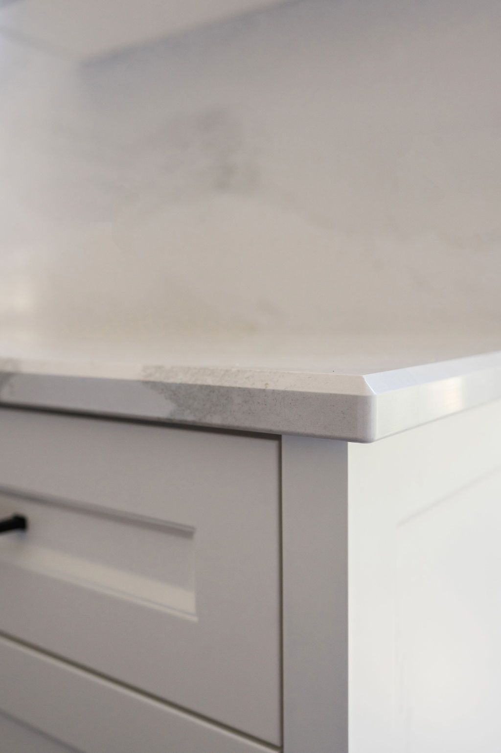 A close up of a white cabinet with a marble counter top.