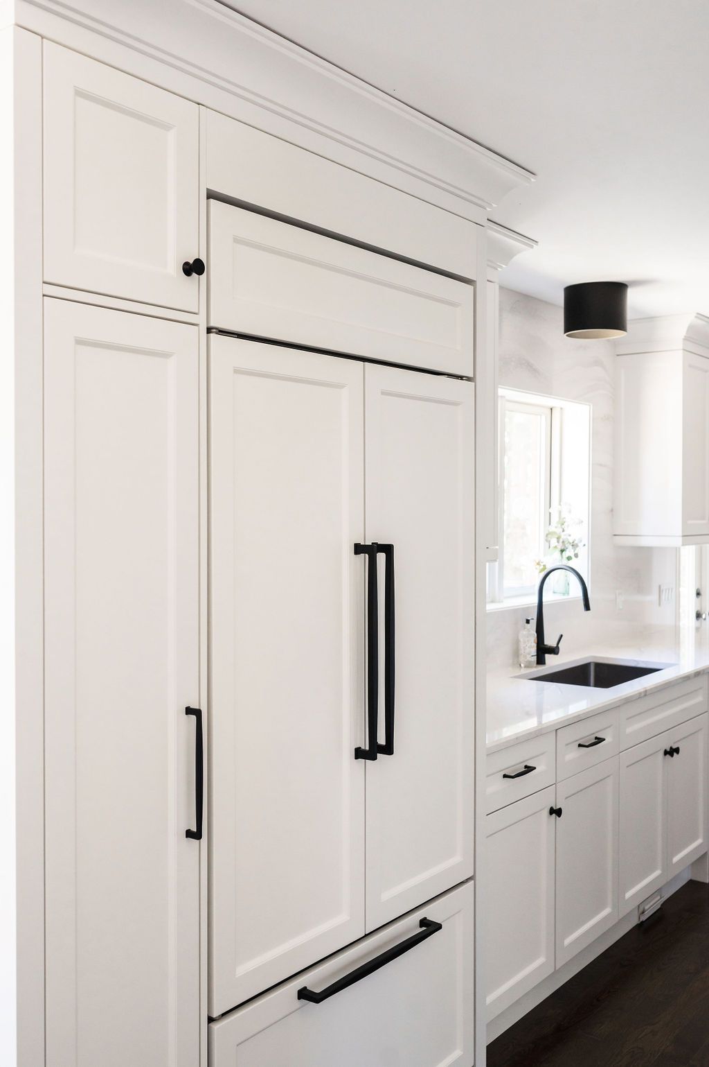 A kitchen with white cabinets and black handles