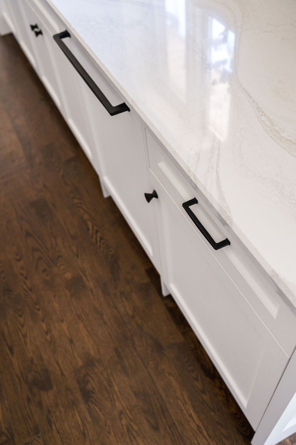 A kitchen counter with white cabinets and black handles