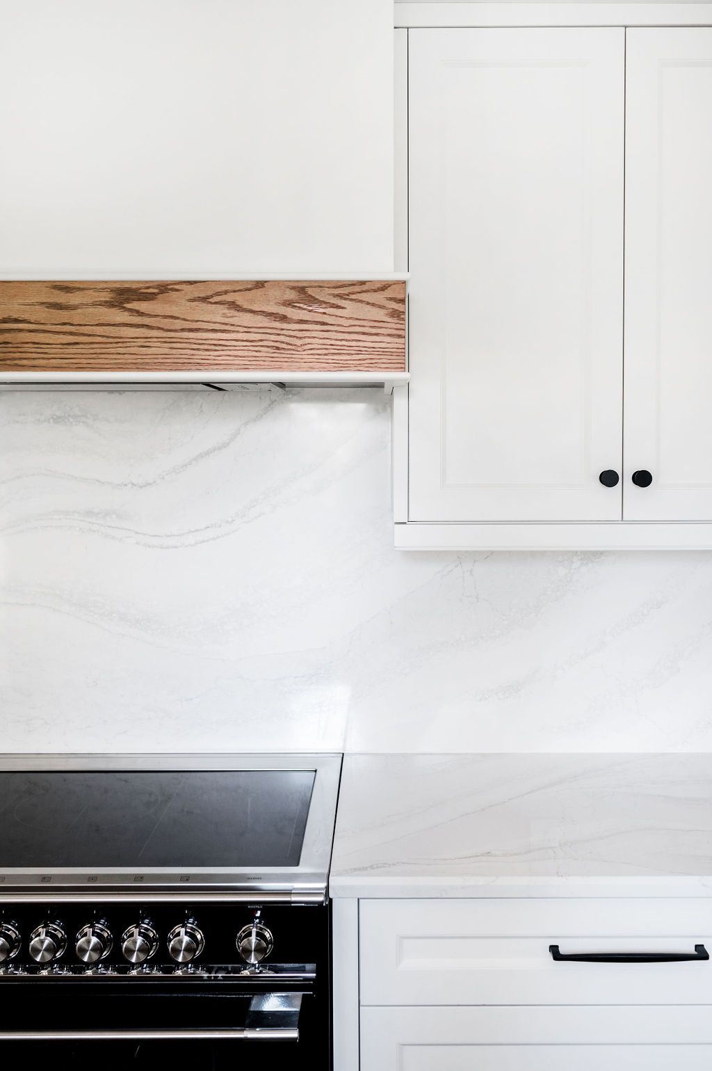 A kitchen with white cabinets and a black stove top oven.